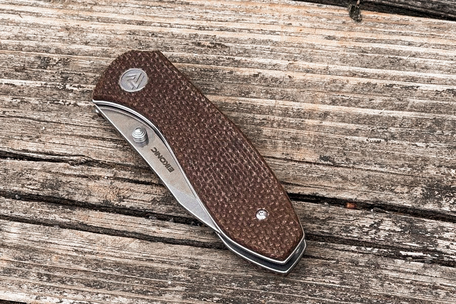 A folding knife on a wood table. 