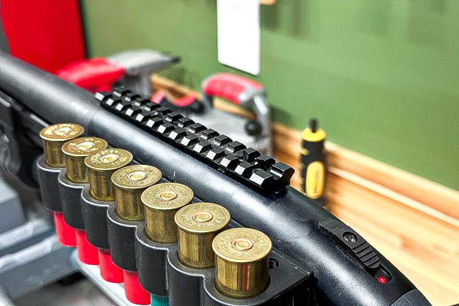 A view of the top of a shotgun receiver with a picatinny rail mounted to the shotgun.