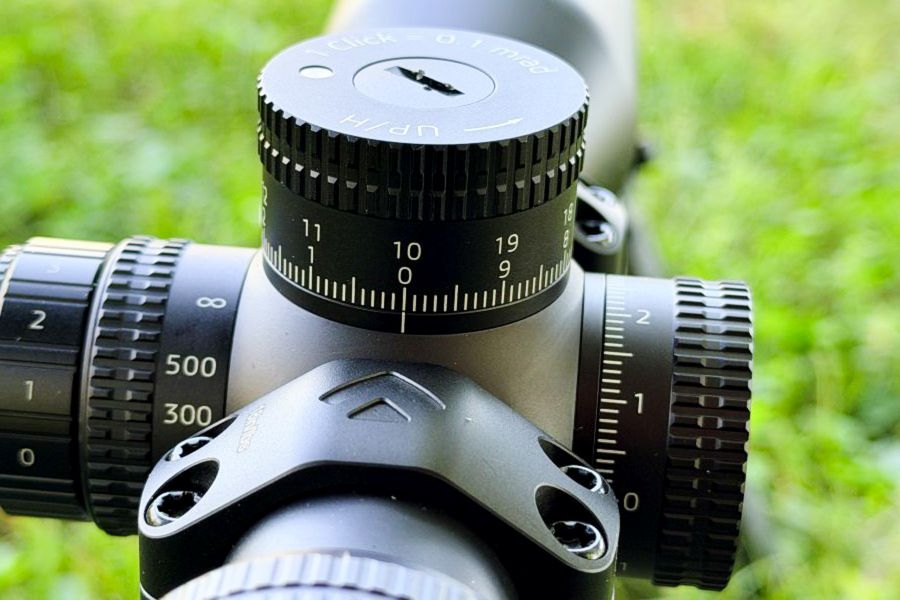 Three black turrets on a black scope with green grass in the background. German Precision Optics Centuri 4x16 Compact Scope